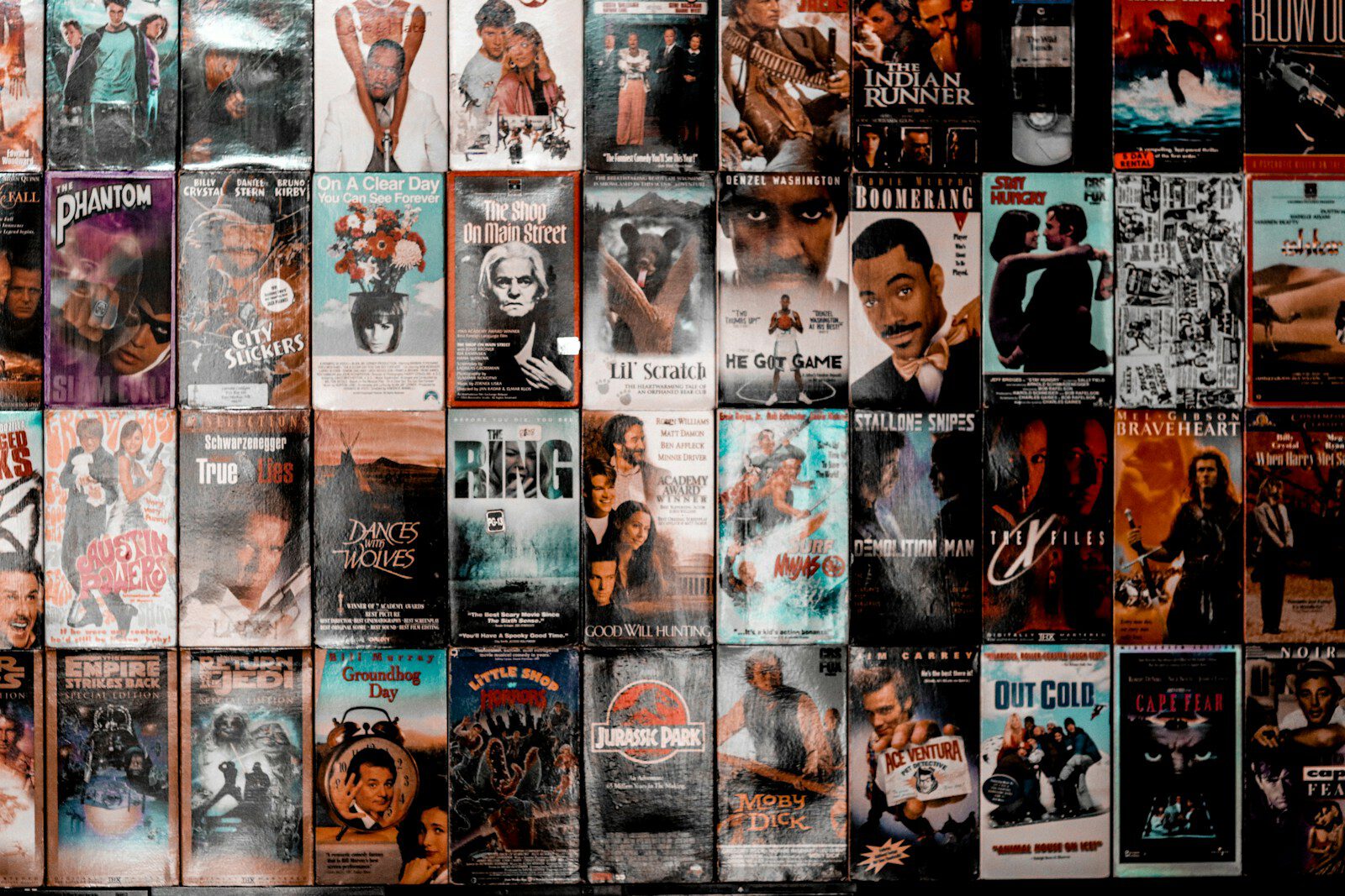 A wall covered with a grid of vintage VHS movie cassette covers