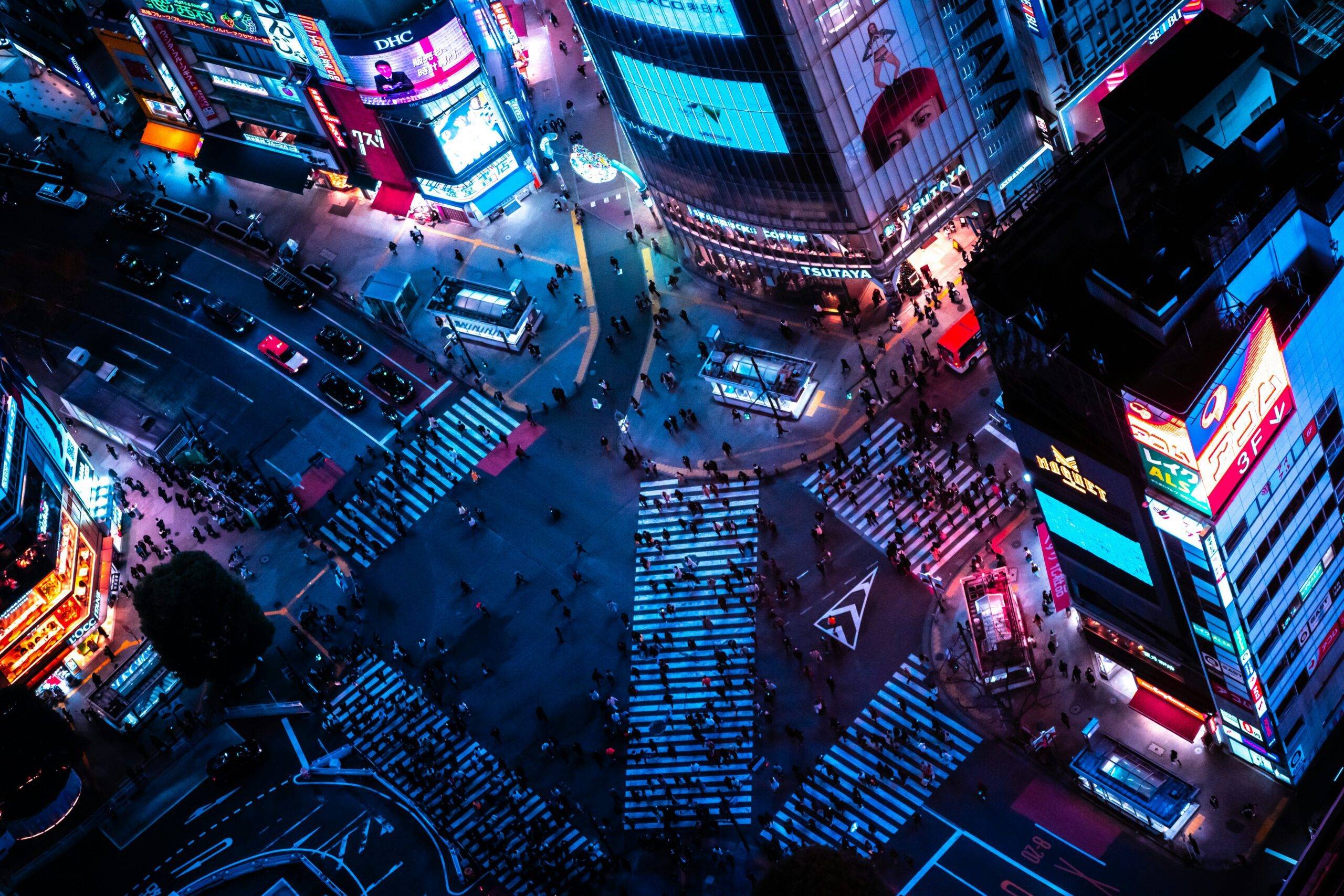 Shibuya crossing at night, lit by neon and busy with people